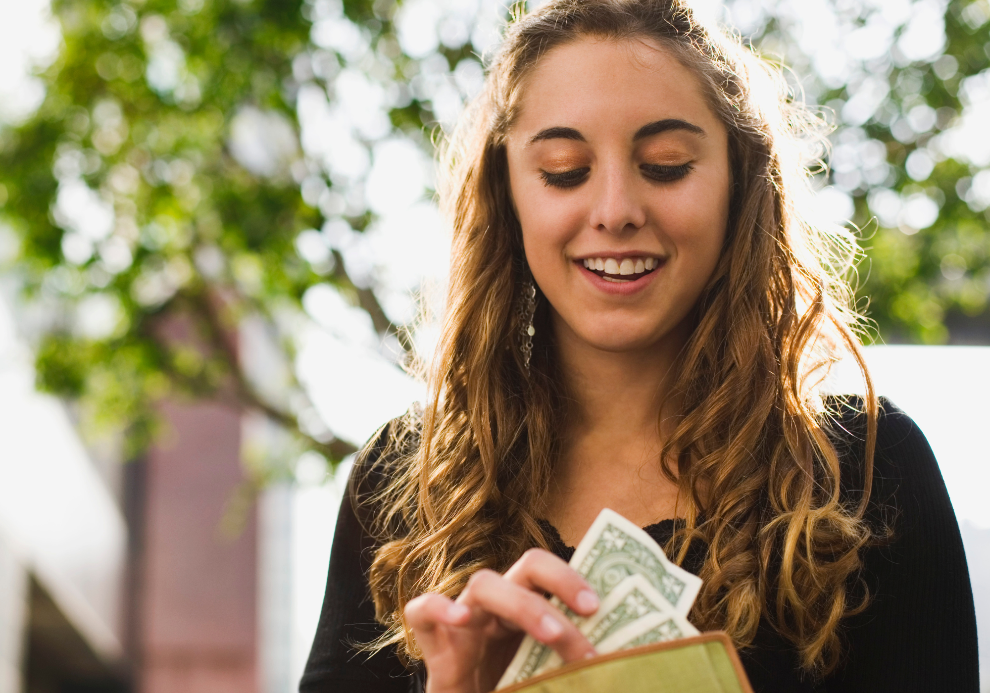 Teenage girl looking into wallet and counting cash