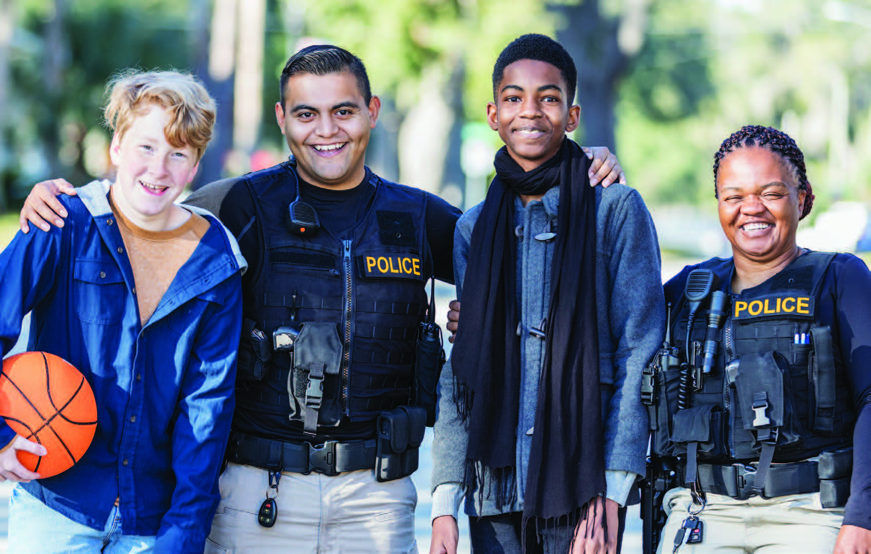 police officers with two kids holding basketball smiling