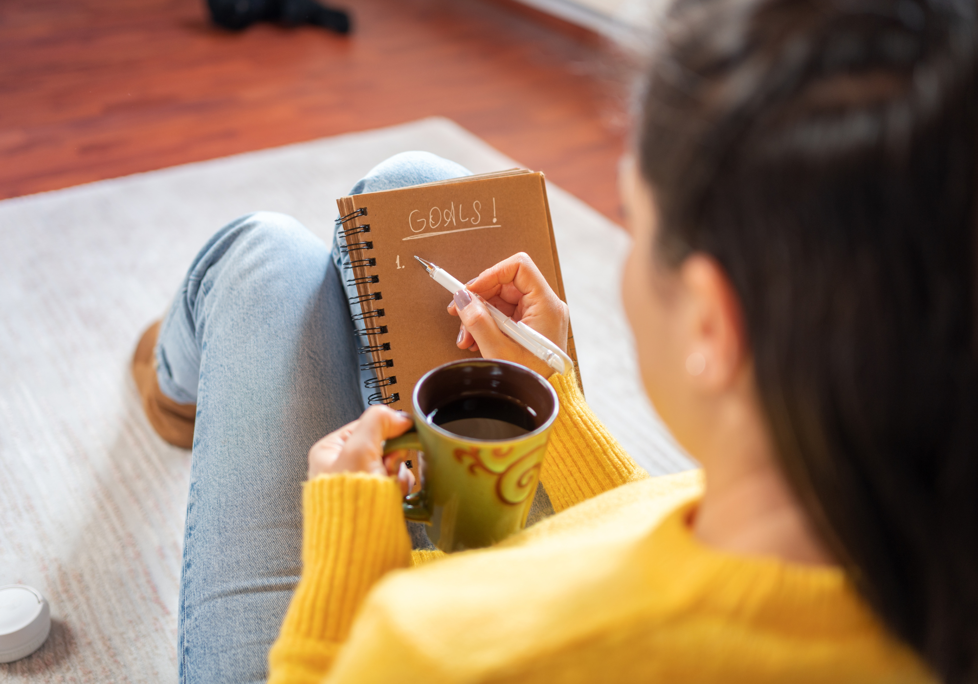 woman writing down New Years' resolutions on notebook