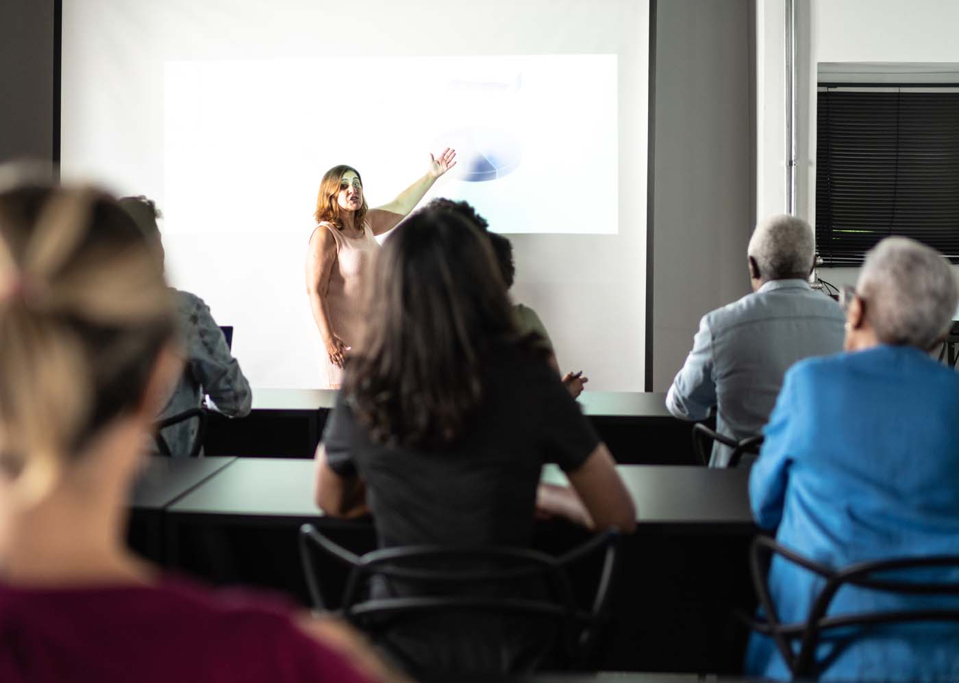 A woman presenting in front of a classroom. 