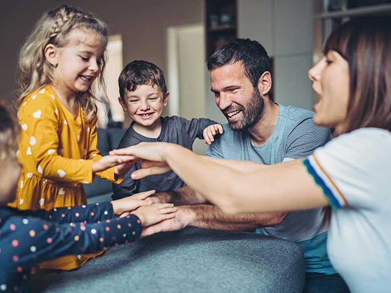 Happy young family at home placing hands on top of one another's. 