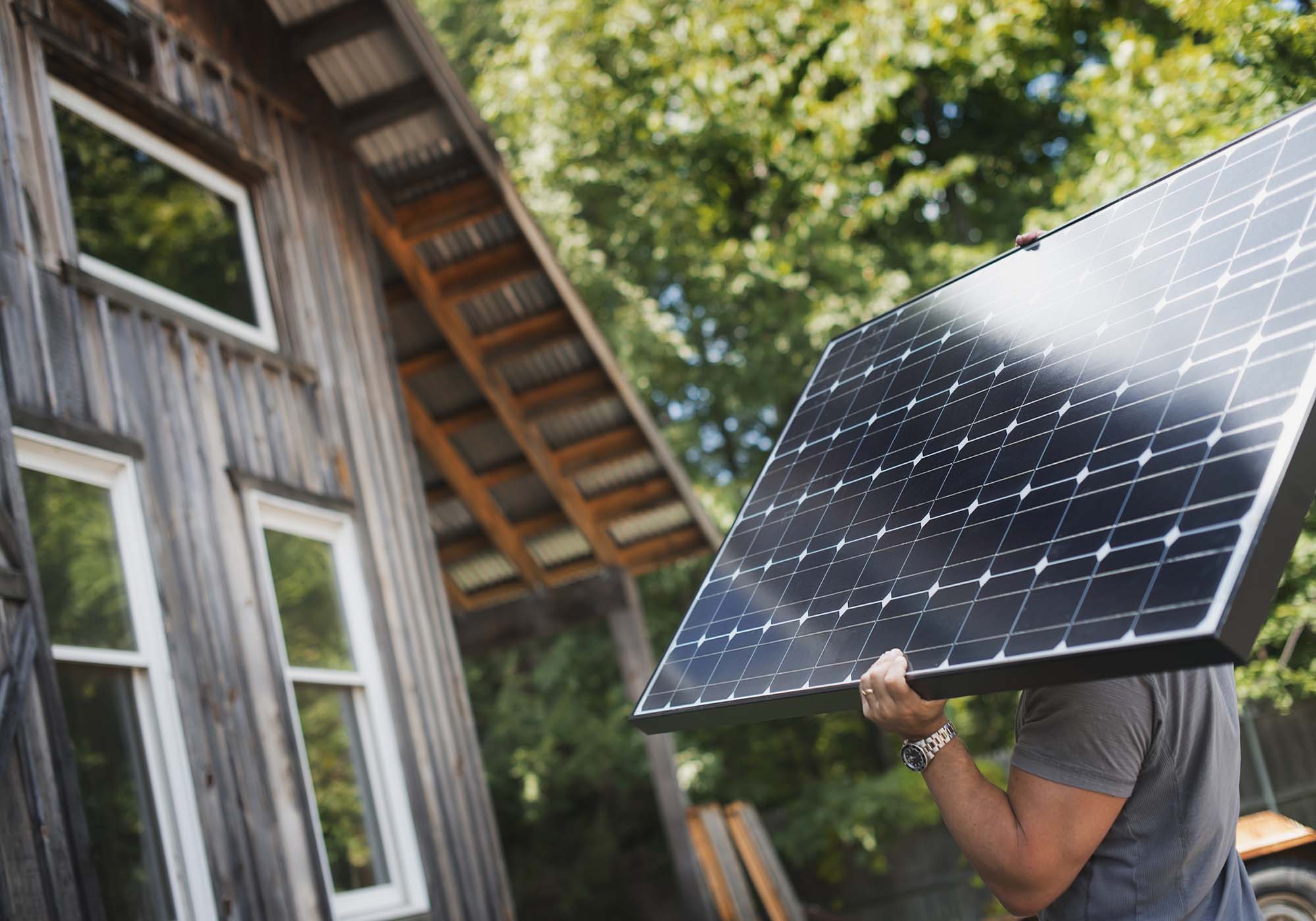 man carrying solar panels to roof of house 