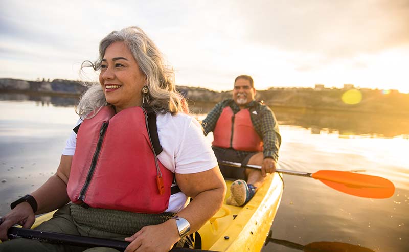 couple sitting on yellow kayak in lake