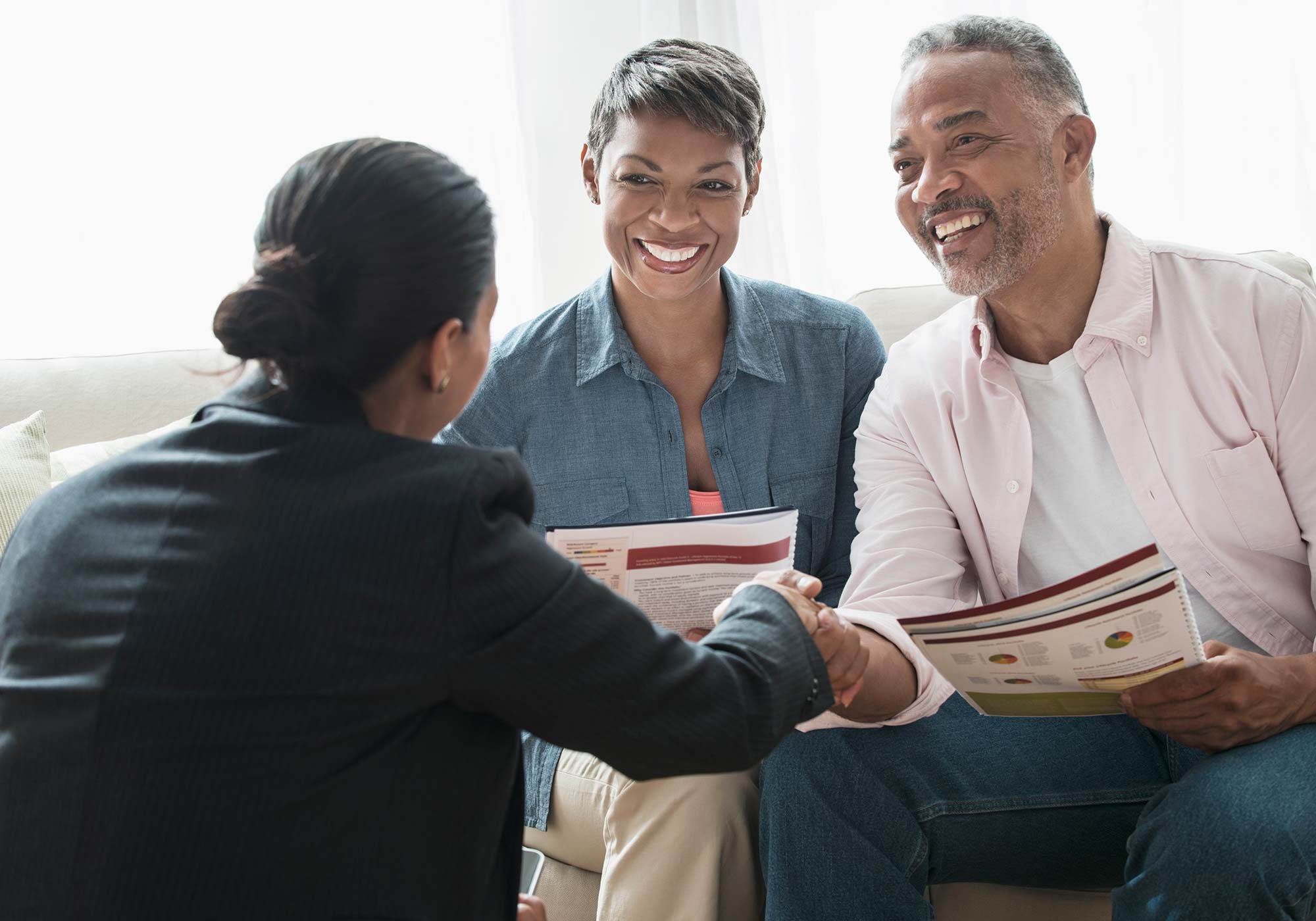 Smiling couple meeting with a financial advisor while holding a finance book.