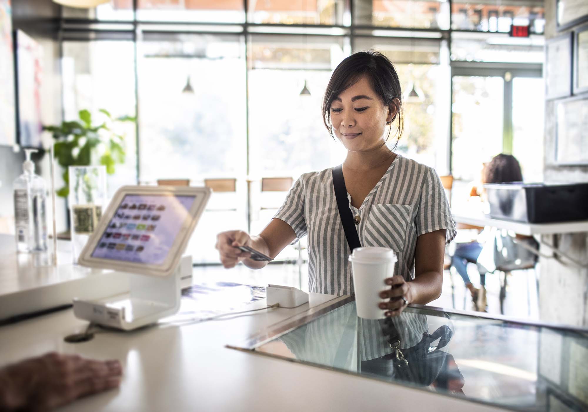 woman using The Police Credit Union card to pay for coffee