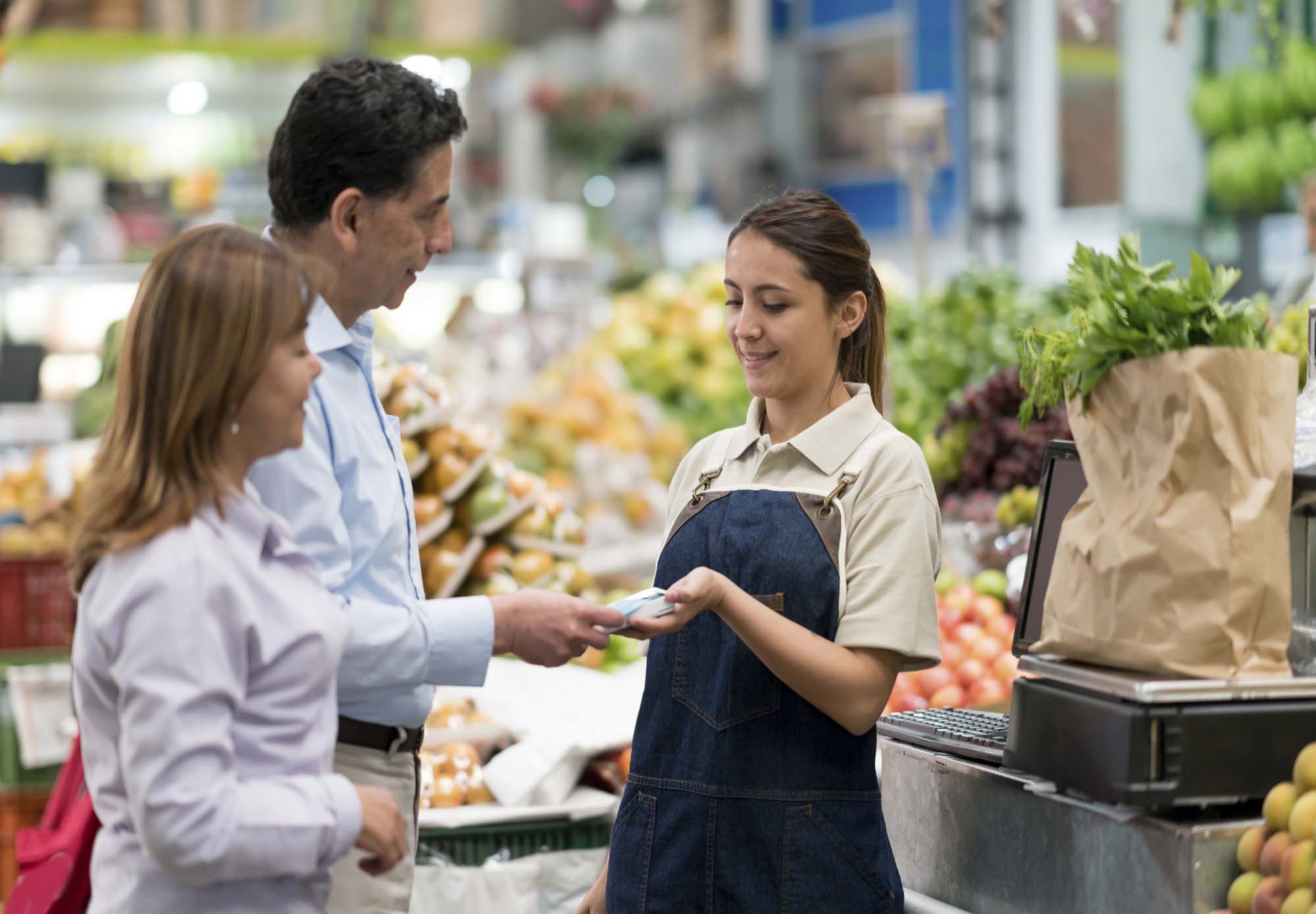 Couple at the grocery store paying with their The Police Credit Union digital card. 